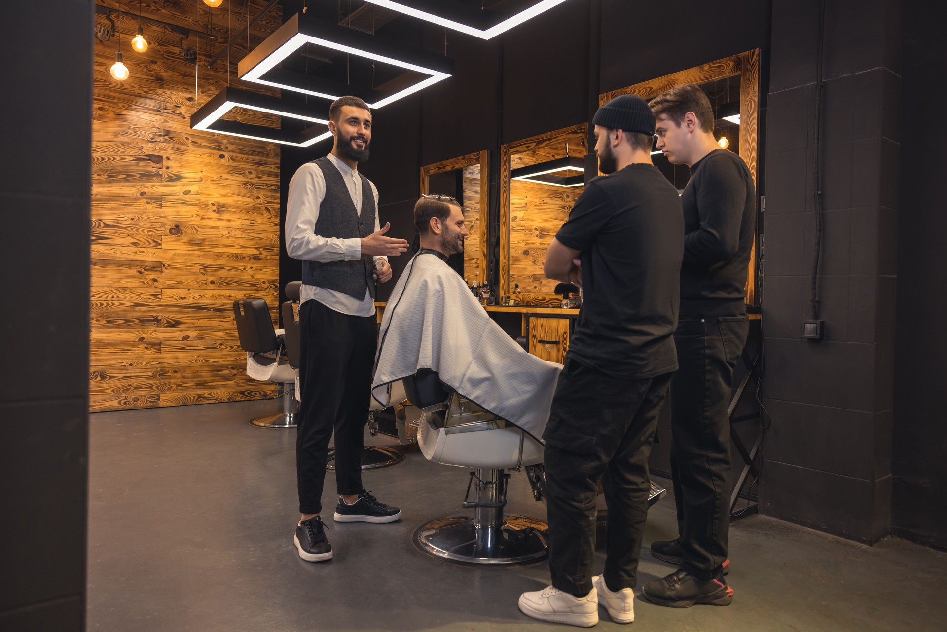 Barber teaches student to make men's hairstyles on model.